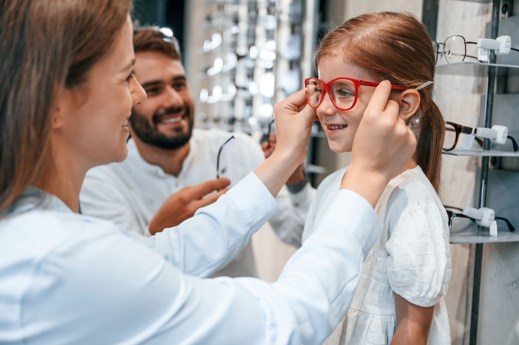 Female Medical/Optometric Assistant trying some eye glasses on a little girl